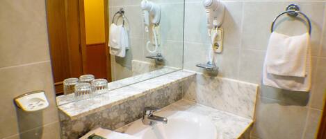 A bathroom with a marble sink, a mirror, a hairdryer, and a towel rack.