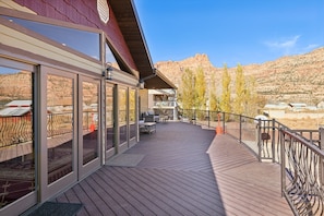 A wooden deck with glass doors leading to a balcony, overlooking a mountainous landscape. - Zion Cliff Lodge (Hildale)