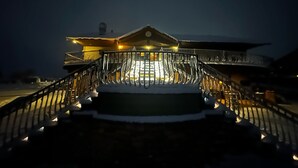 A snow-covered outdoor area leading to a building with a balcony and railing, illuminated by warm lights. - Zion Cliff Lodge (Hildale)
