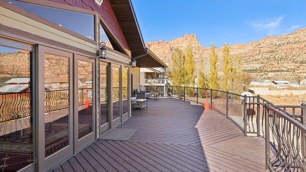 A wooden deck with glass doors and a metal railing, overlooking a mountainous landscape. - Zion Cliff Lodge (Hildale)