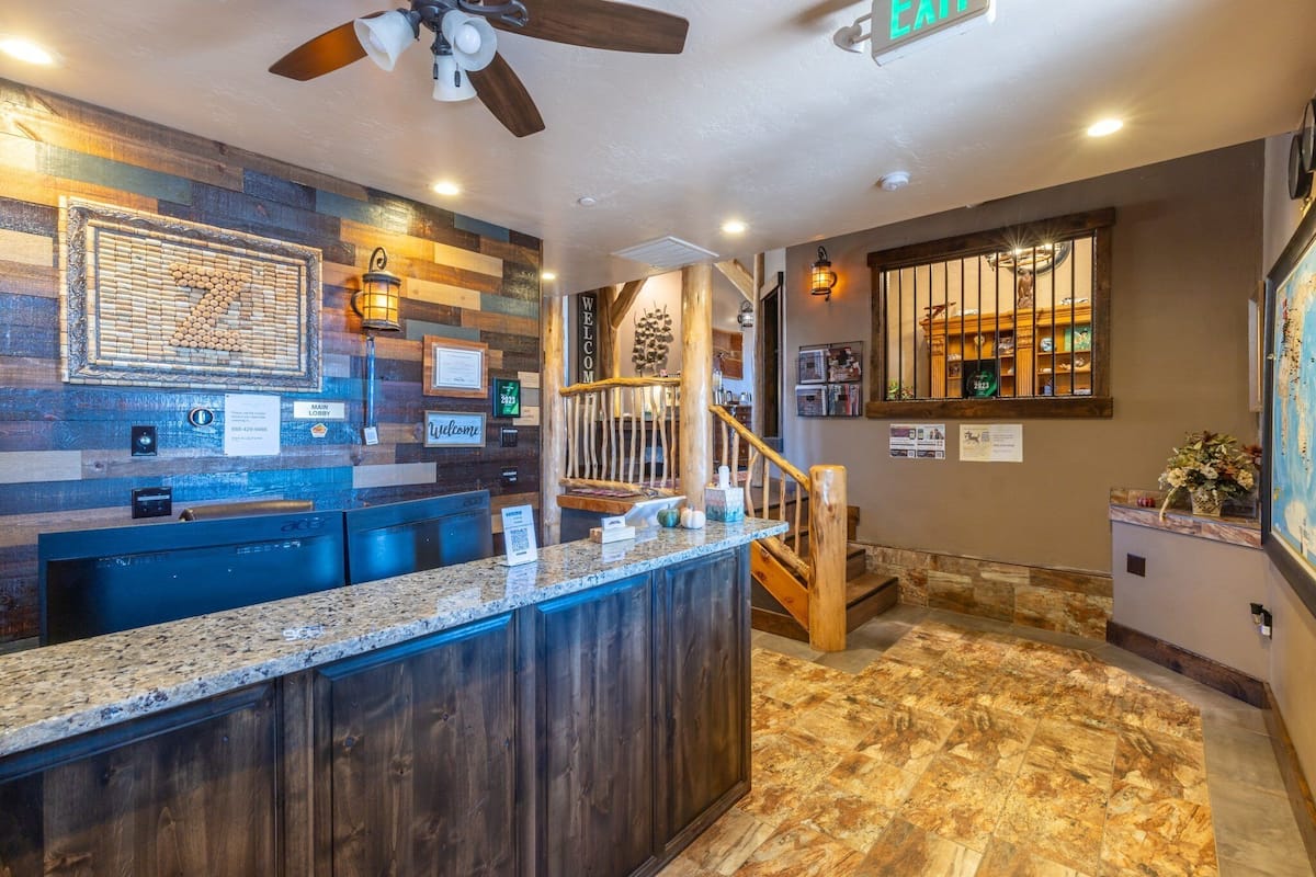 A reception area with a wooden counter, a ceiling fan, and a staircase leading to an upper level.