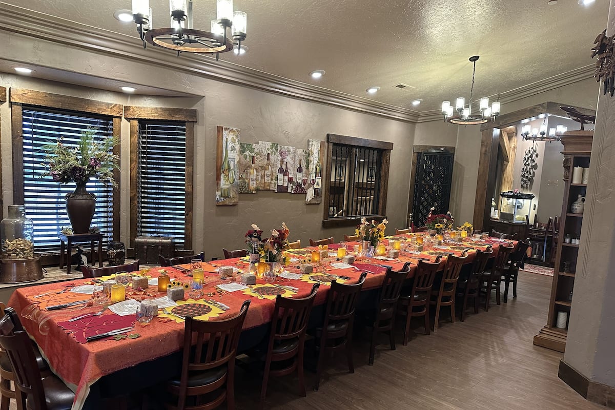 A long dining table set for a meal, with chairs around it.