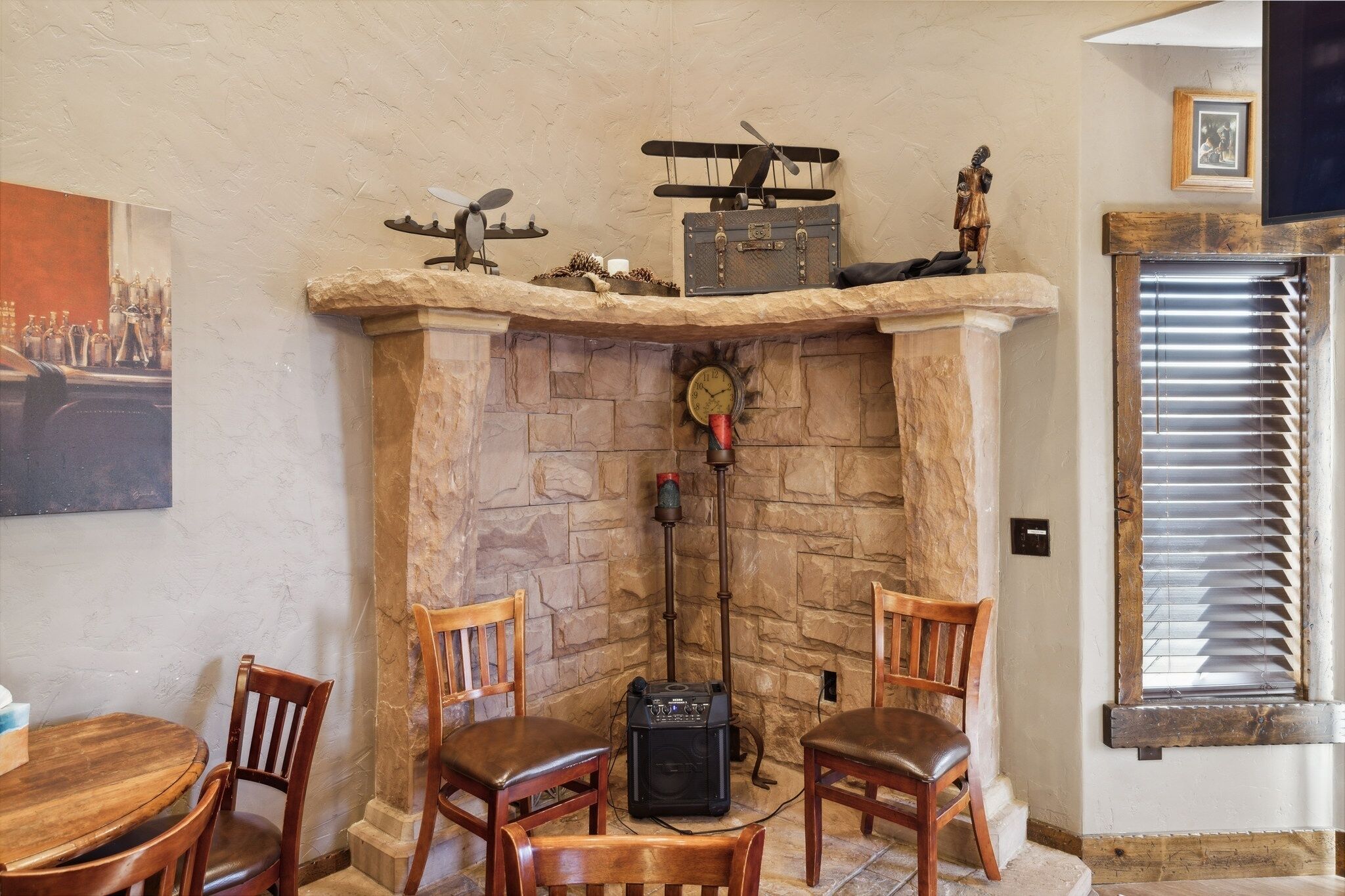 A cozy room with a stone fireplace, wooden chairs, and a table.