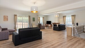 Een ruime woonkamer met een flatscreen televisie, een houten salontafel en een trap naar een hoger gelegen verdieping.