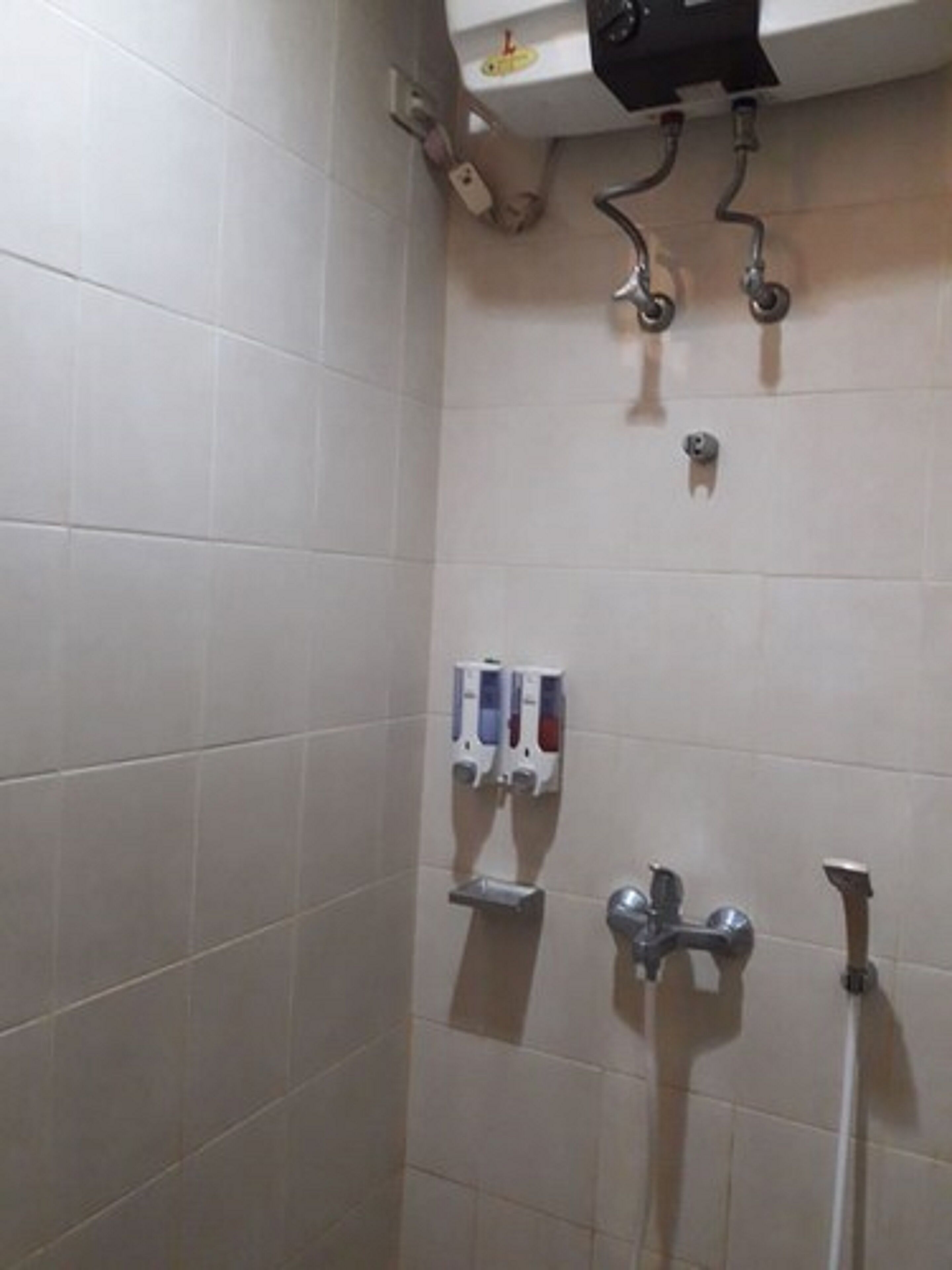 A bathroom with a shower, a hand dryer, and a soap dispenser.