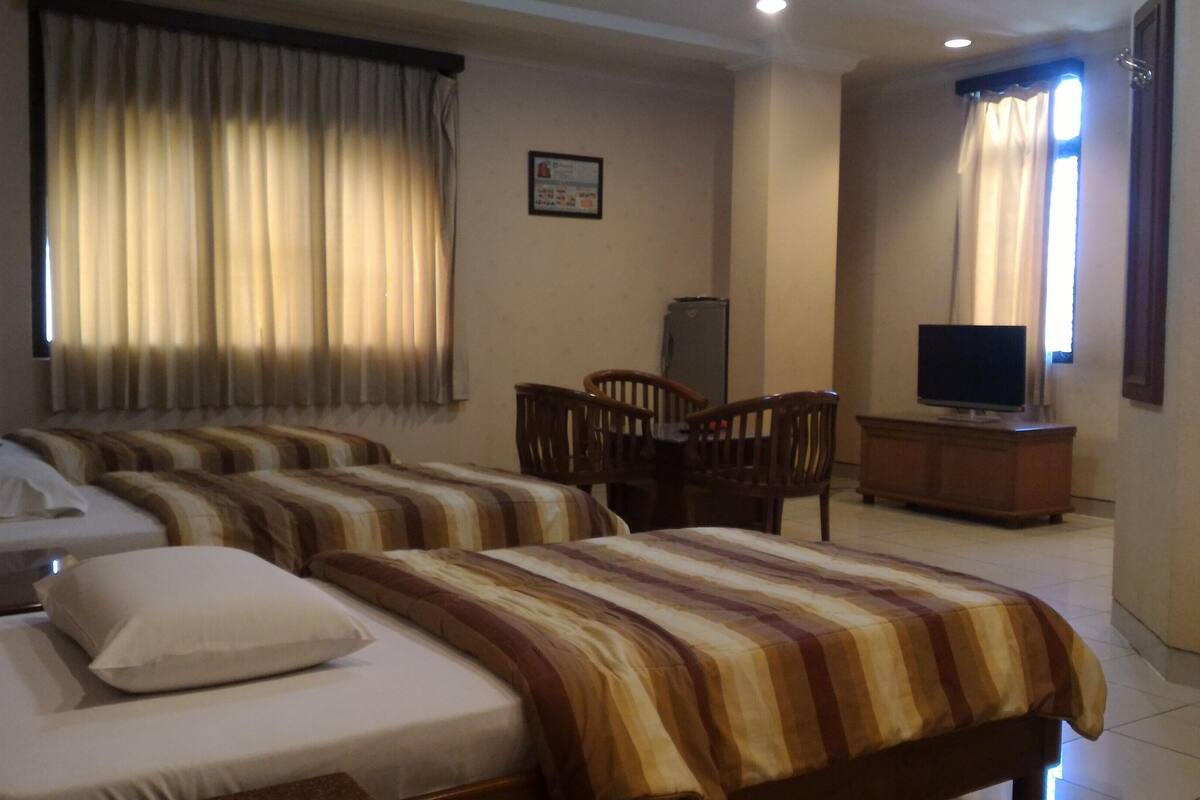 A hotel room with two beds, a desk, a chair, a television, and curtains.