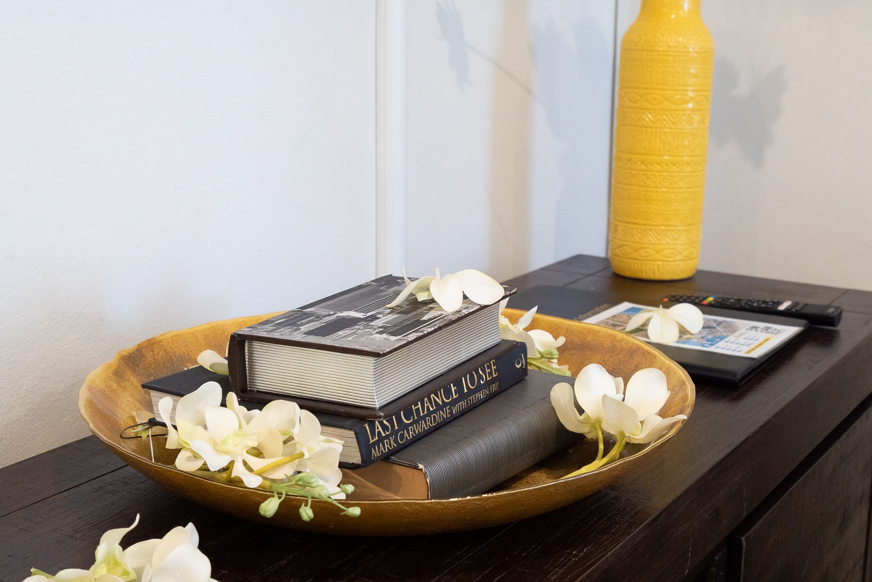 Una bandeja de madera con libros y flores blancas sobre una mesa de madera oscura.