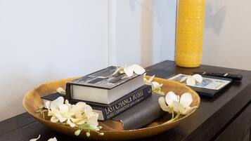 Una bandeja de madera con libros y flores blancas sobre una mesa de madera oscura.