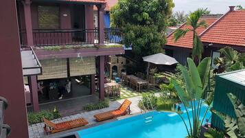 A pool area with lounge chairs, a table, and a staircase leading to a covered deck.