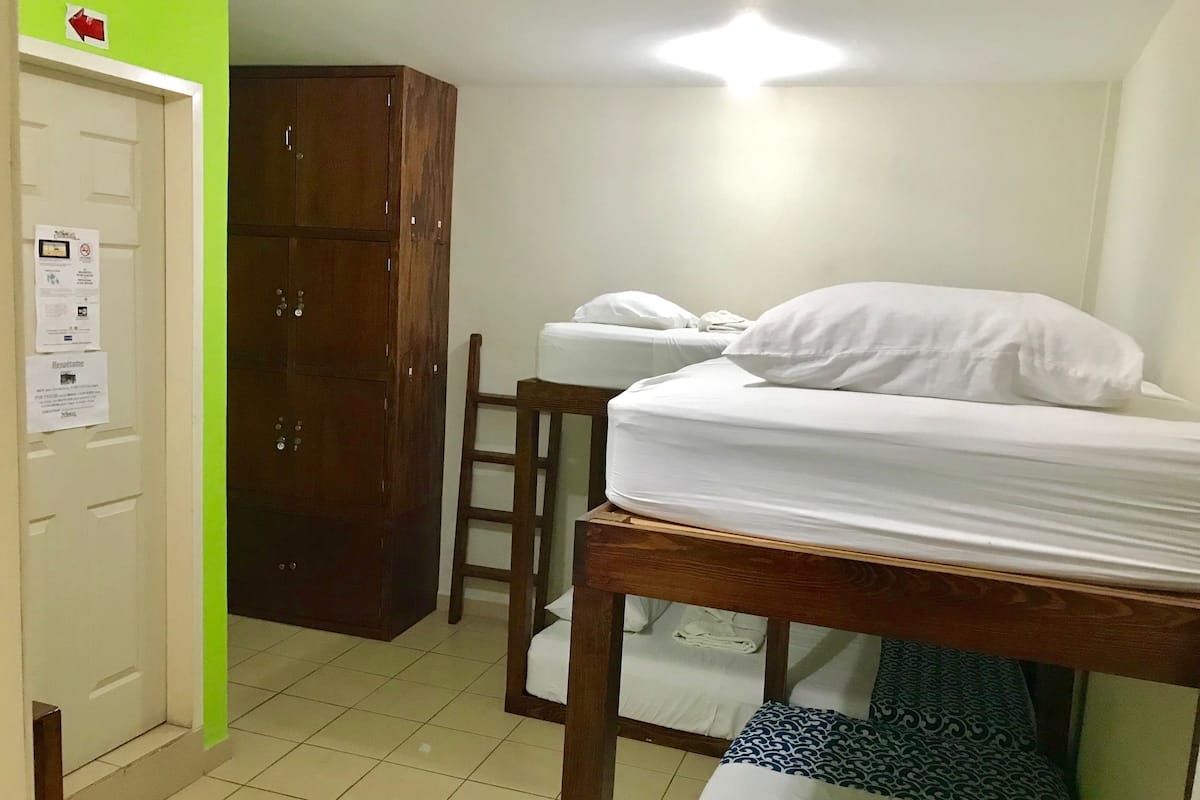 A room with two beds, a wooden wardrobe, and a door with a sign.