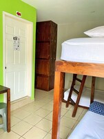 Una habitación con una cama litera, un armario de madera, un escritorio con silla y una puerta con un cartel.