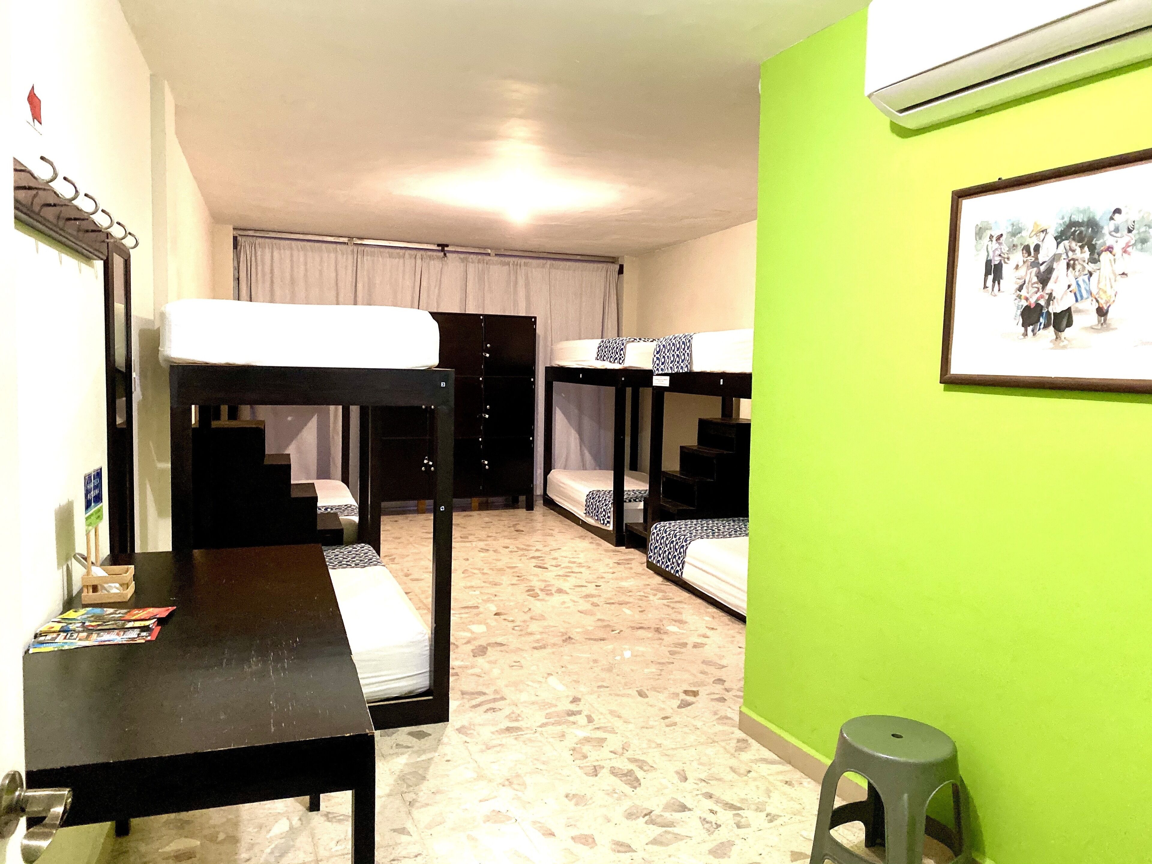 Ein Schlafsaalzimmer mit Etagenbetten, einem Tisch und einer grünen Wand.