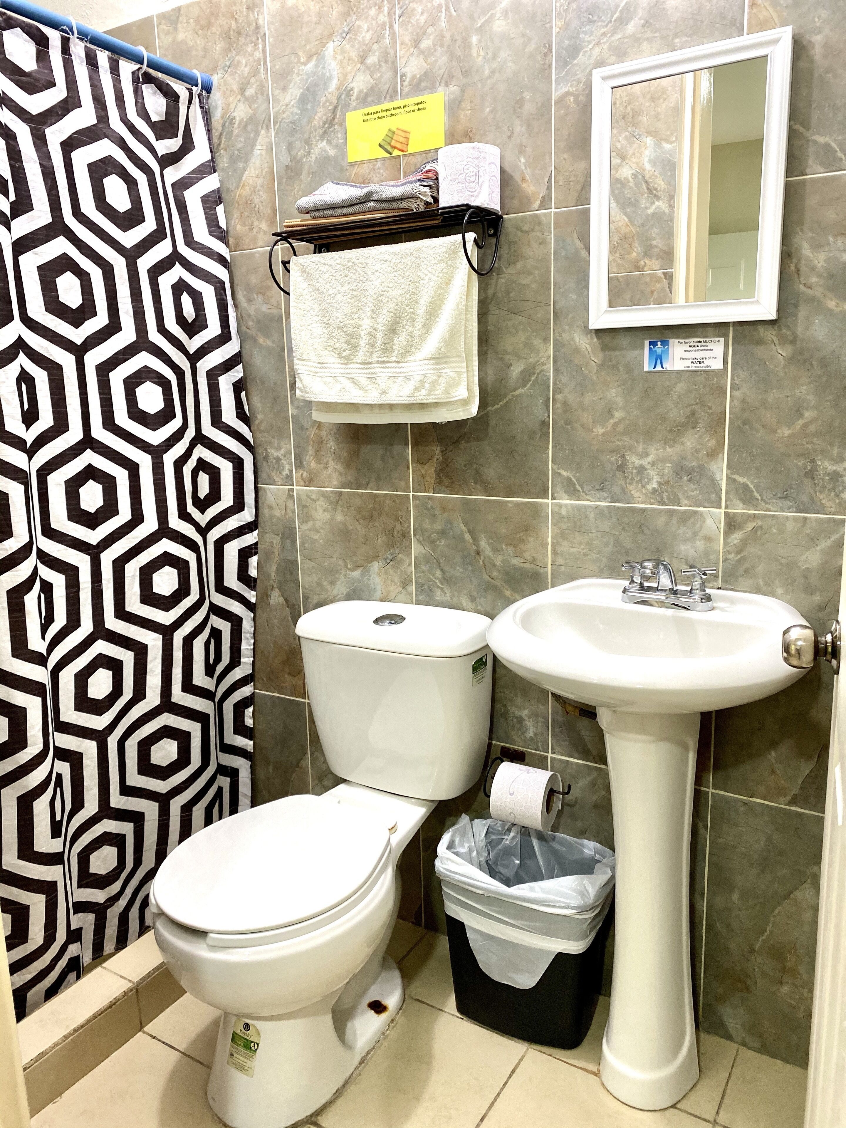 A bathroom with a toilet, sink, and shower curtain.