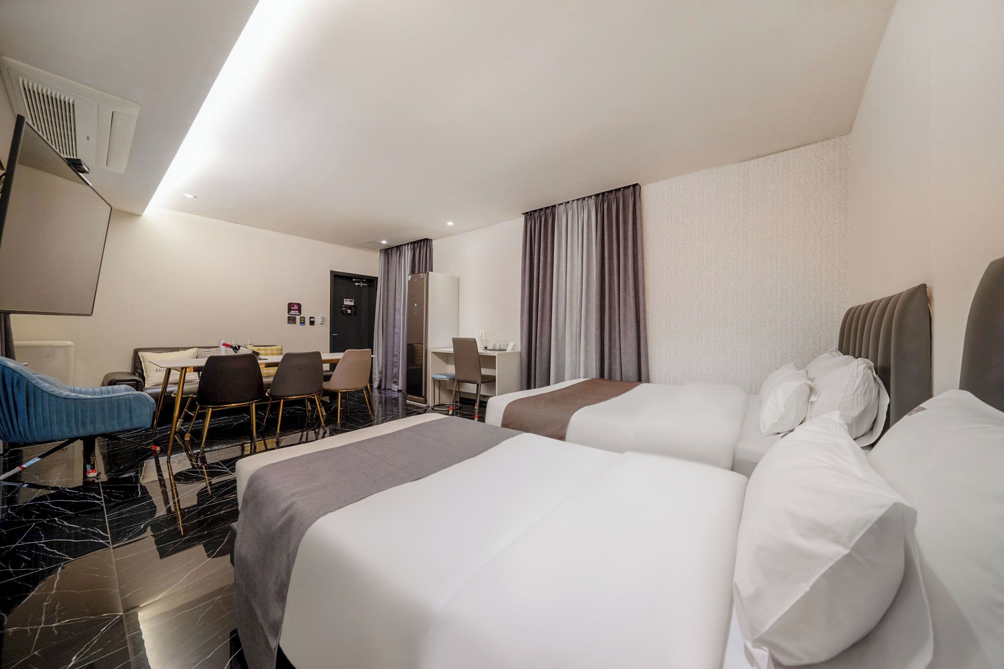 Habitación de hotel con dos camas, un escritorio, sillas y una televisión.