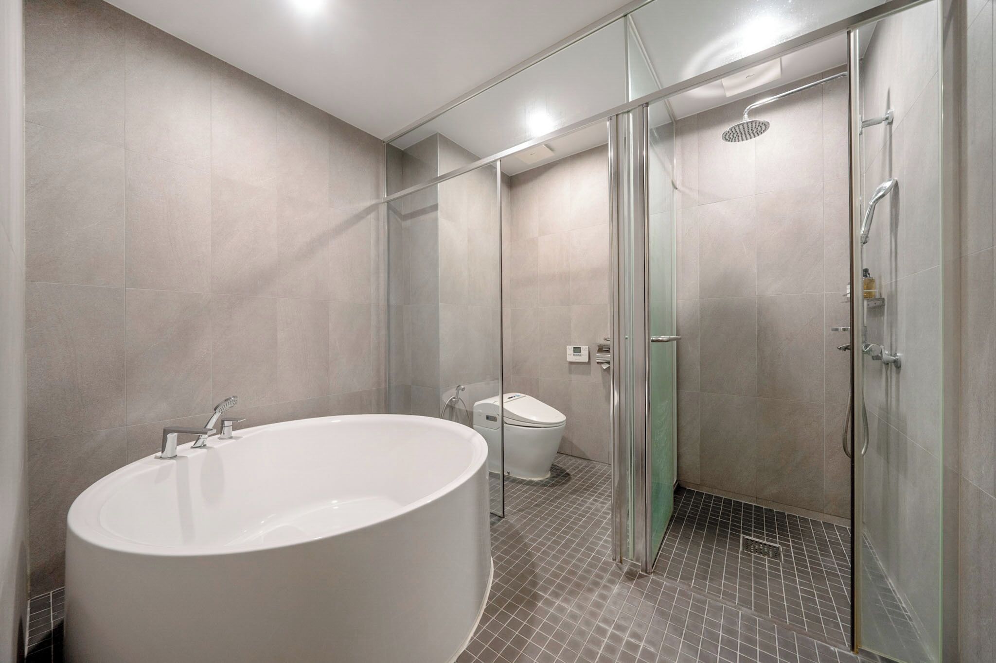 A modern bathroom with a large bathtub, a glass-enclosed shower, and a toilet.