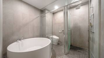 A modern bathroom with a large bathtub, a glass-enclosed shower, and a toilet.