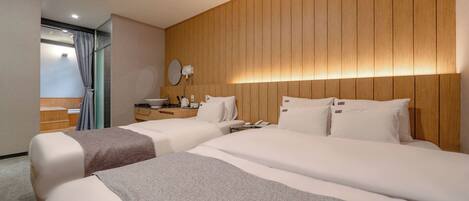 Une chambre d’hôtel avec deux lits, une tête de lit en bois, une table de chevet avec une lampe et une vue sur un espace sauna.