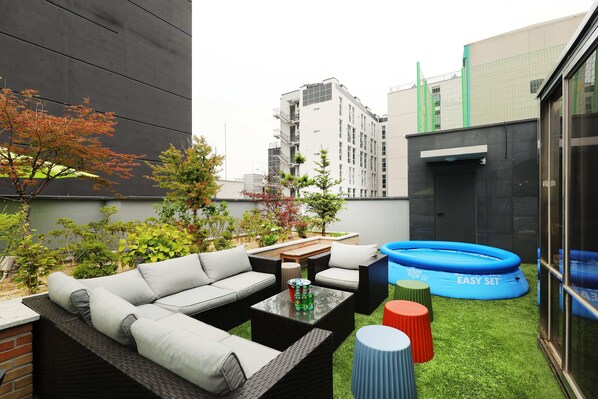 Un patio al aire libre con un conjunto de sofá, una mesita y una piscina inflable azul.