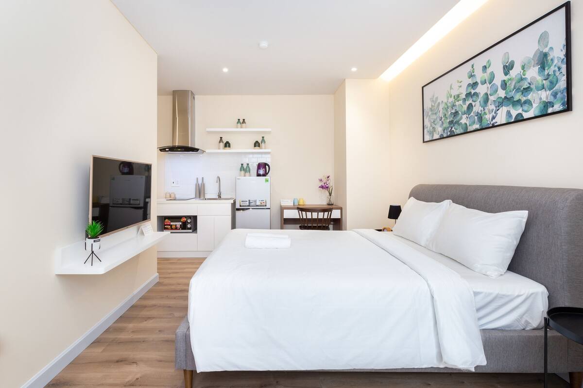 Une chambre d’hôtel moderne dotée d’un grand lit, d’une télévision, d’une kitchenette et d’un coin repas.