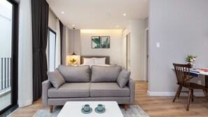 Una sala de estar moderna con un sofá gris, una mesa de centro blanca y una zona de comedor con una silla y una mesa de madera.