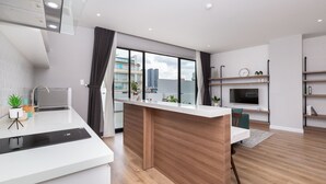 Una cocina moderna con una isla central, horno empotrado y un amplio ventanal con vistas a la ciudad.