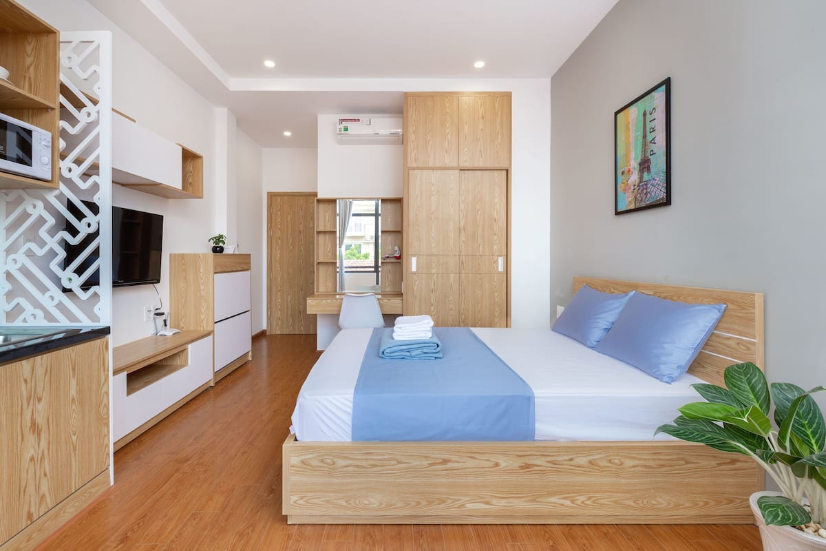 A modern bedroom with a wooden bed, a built-in desk, and a large window.