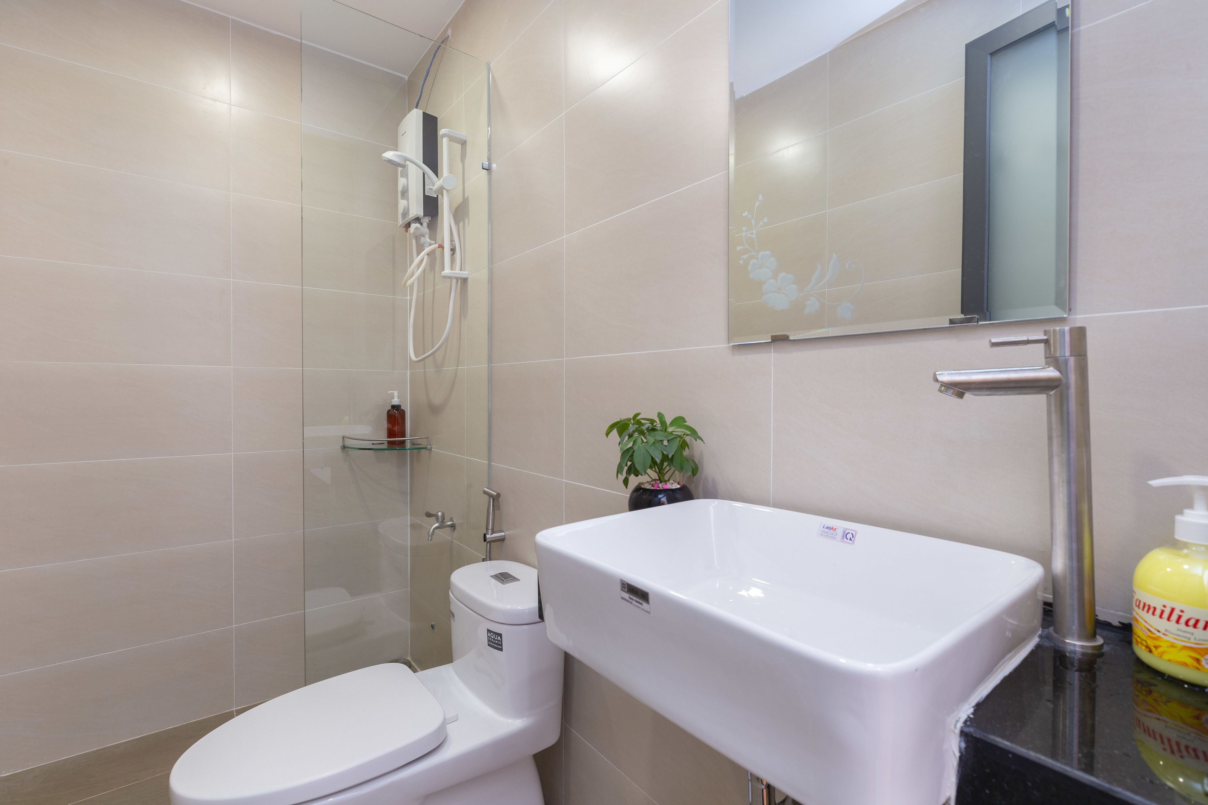 Uma casa de banho moderna com sanita, chuveiro e lavatório.