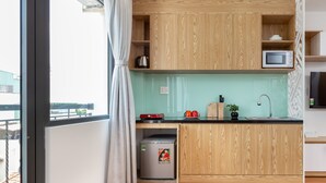 A modern kitchen with wooden cabinets, a microwave, a kettle, and a refrigerator. - Cozrum Homes Ly Chinh Thang (Ho Chi Minh City)