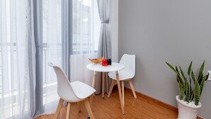 A room with a round table, two white chairs, a potted plant, and a window with sheer curtains. - Cozrum Homes Ly Chinh Thang (Ho Chi Minh City)