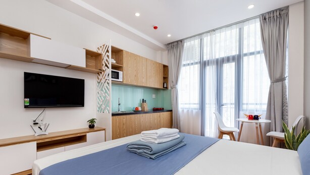 A modern hotel room with a bed, a TV, a kitchenette, and a dining area. - Cozrum Homes Ly Chinh Thang (Ho Chi Minh City)