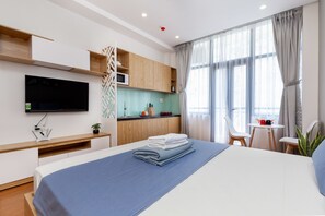 Una habitación de hotel moderna con cama, televisión, kitchenette y zona de comedor.