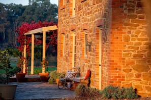 Un edificio de piedra con una pérgola de madera y plantas en macetas.