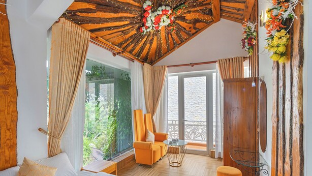 A room with a bed, a chair, a small table, and a wardrobe. - Mac Valley Dalat Hotel (Xuan Huong - Da Lat)