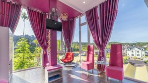 A modern room with large windows, a TV, a red chair, and a small table. - Mac Valley Dalat Hotel (Xuan Huong - Da Lat)
