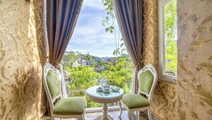 A room with a view of a town, a round table with chairs, and a window with curtains. - Mac Valley Dalat Hotel (Xuan Huong - Da Lat)