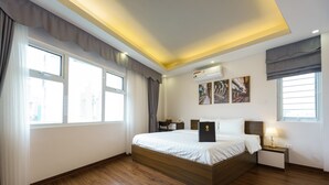 Une chambre d’hôtel moderne avec un grand lit, une table de chevet avec une lampe et des œuvres d’art accrochées au mur.