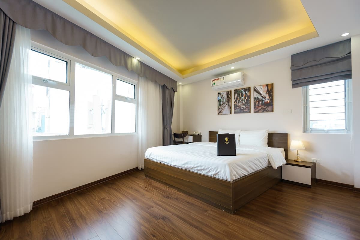 Habitación de hotel moderna con una cama grande, una mesita de noche con lámpara y una obra de arte en la pared.