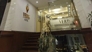 L’extérieur de l’hôtel Veris se distingue par son entrée imposante, sa façade en marbre et un escalier menant à l’entrée.