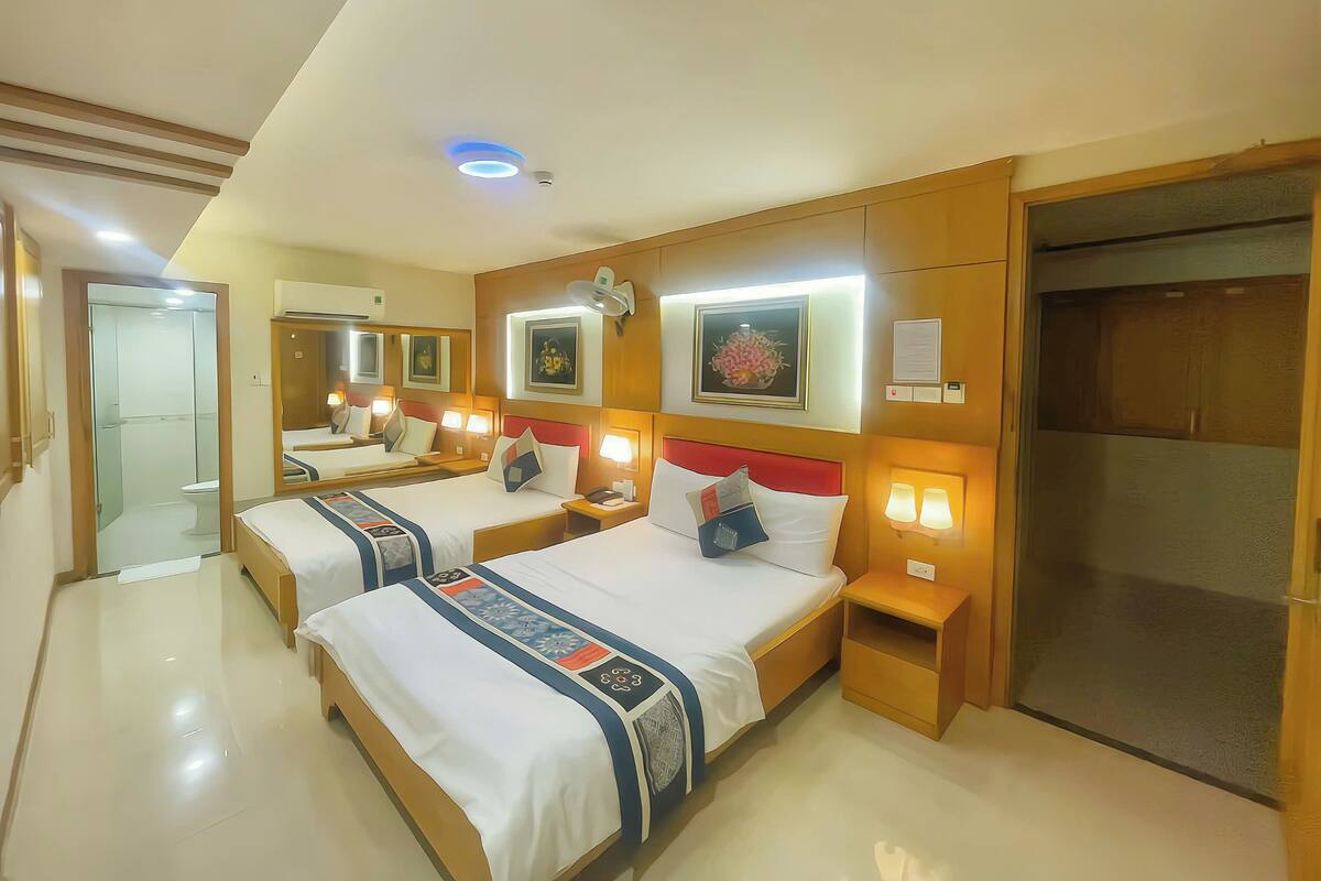 Een hotelkamer met twee bedden, nachtkastjes, een spiegel en een kledingkast.