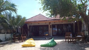 A house with a tiled roof, a covered patio with chairs, and a stone wall. - Bale Gerupuk (Kuta)