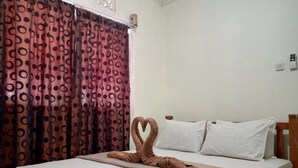 A hotel room with a bed, a heart-shaped towel arrangement, and a curtain with a circular pattern. - Bale Gerupuk (Kuta)