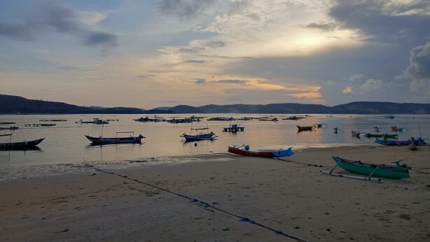 A beach with boats anchored in the water and a clear sky. - Bale Gerupuk (Kuta)