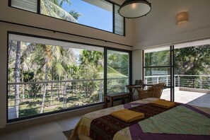 A bedroom with large windows, a bed, a desk, and a chair. - Davey's Town House (Shrirangapattana)