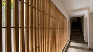 Un pasillo con pared de listones de madera y una escalera que sube a un piso superior.