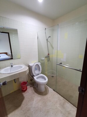 A bathroom with a toilet, sink, and glass-enclosed shower area. - Subhamitra Hotel Hua Hin (Hua Hin)