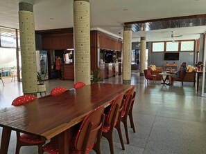 A spacious dining area with a long wooden table and red chairs, a kitchen area with a counter, and a living room with seating. - Subhamitra Hotel Hua Hin (Hua Hin)