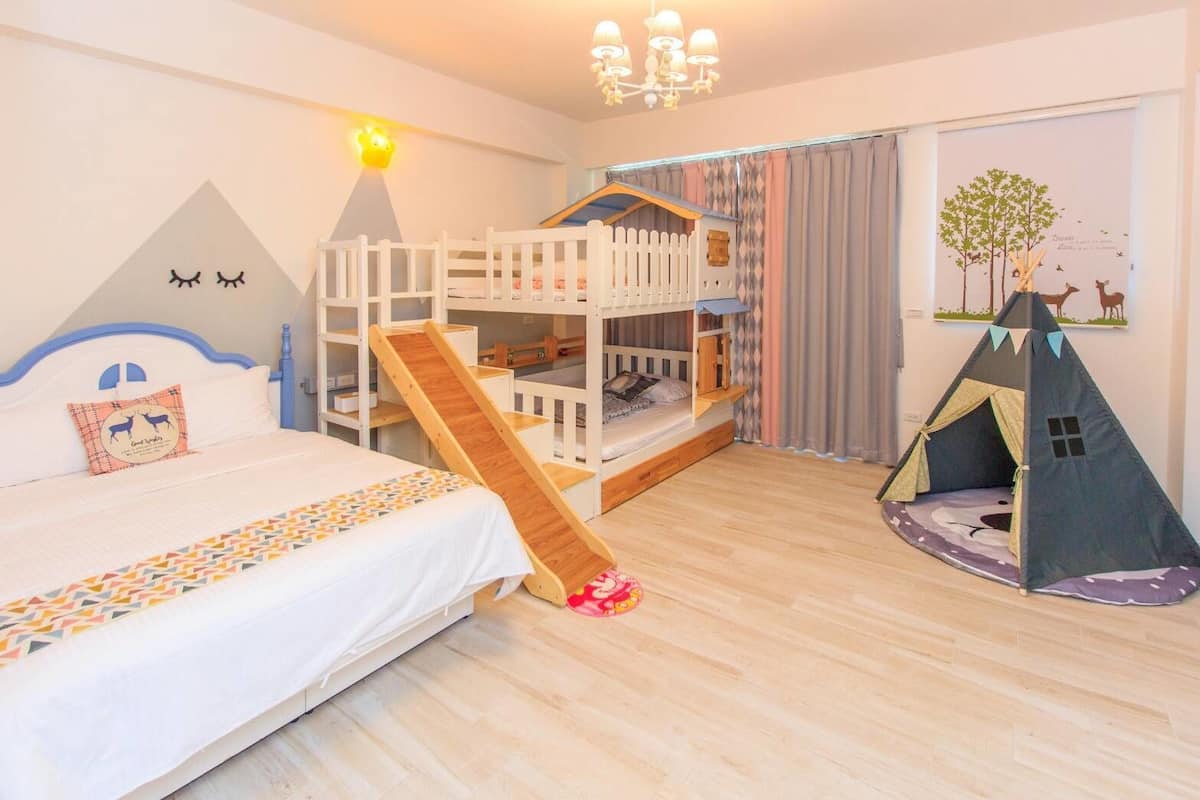 A child's bedroom with bunk beds, a slide, a tent, and a wall decoration.