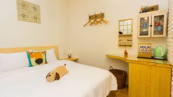 A neatly arranged bedroom with a bed, a wooden dresser, a small table, and a wall-mounted drying rack.