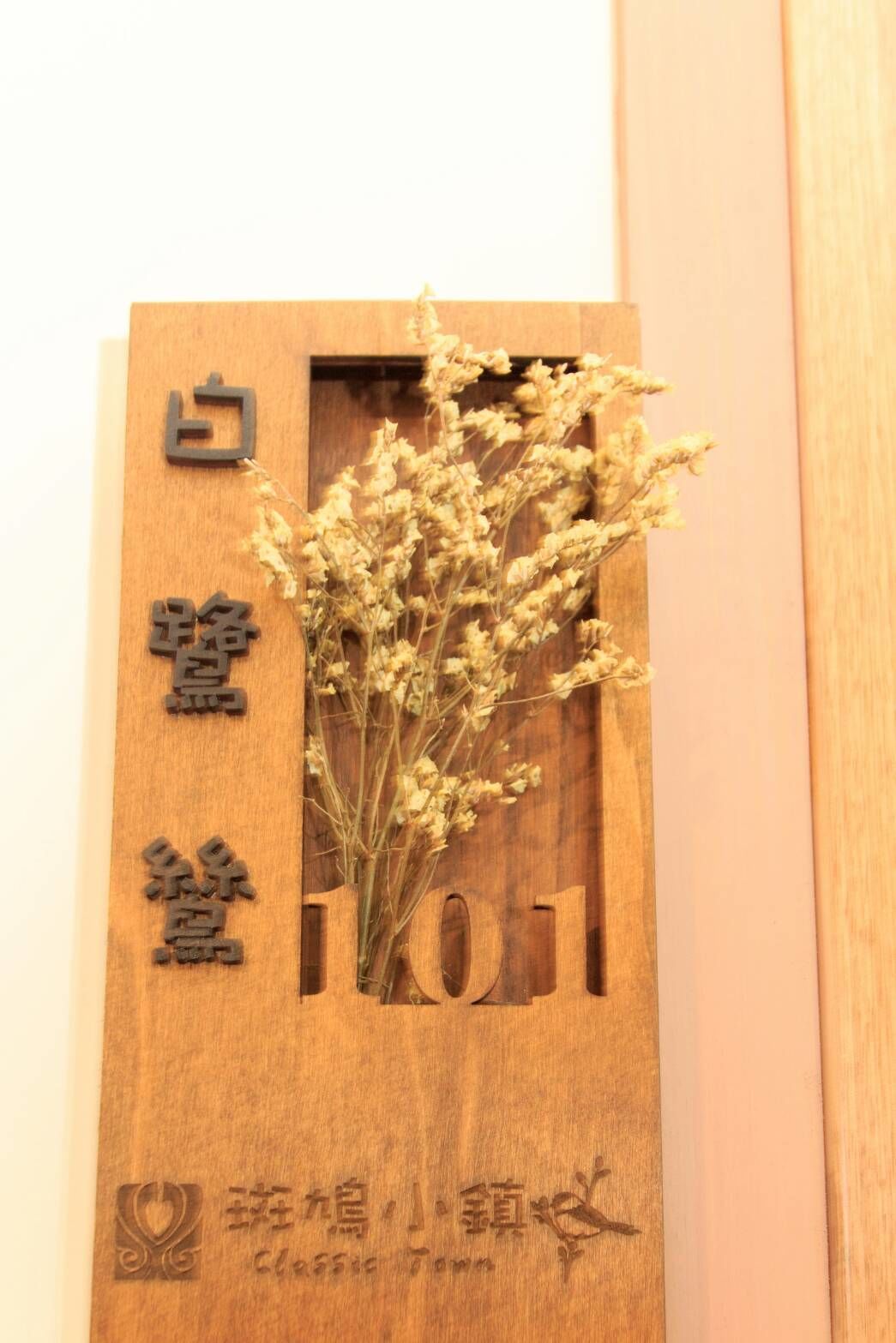 Un letrero de madera con texto grabado y un arreglo de flores secas.