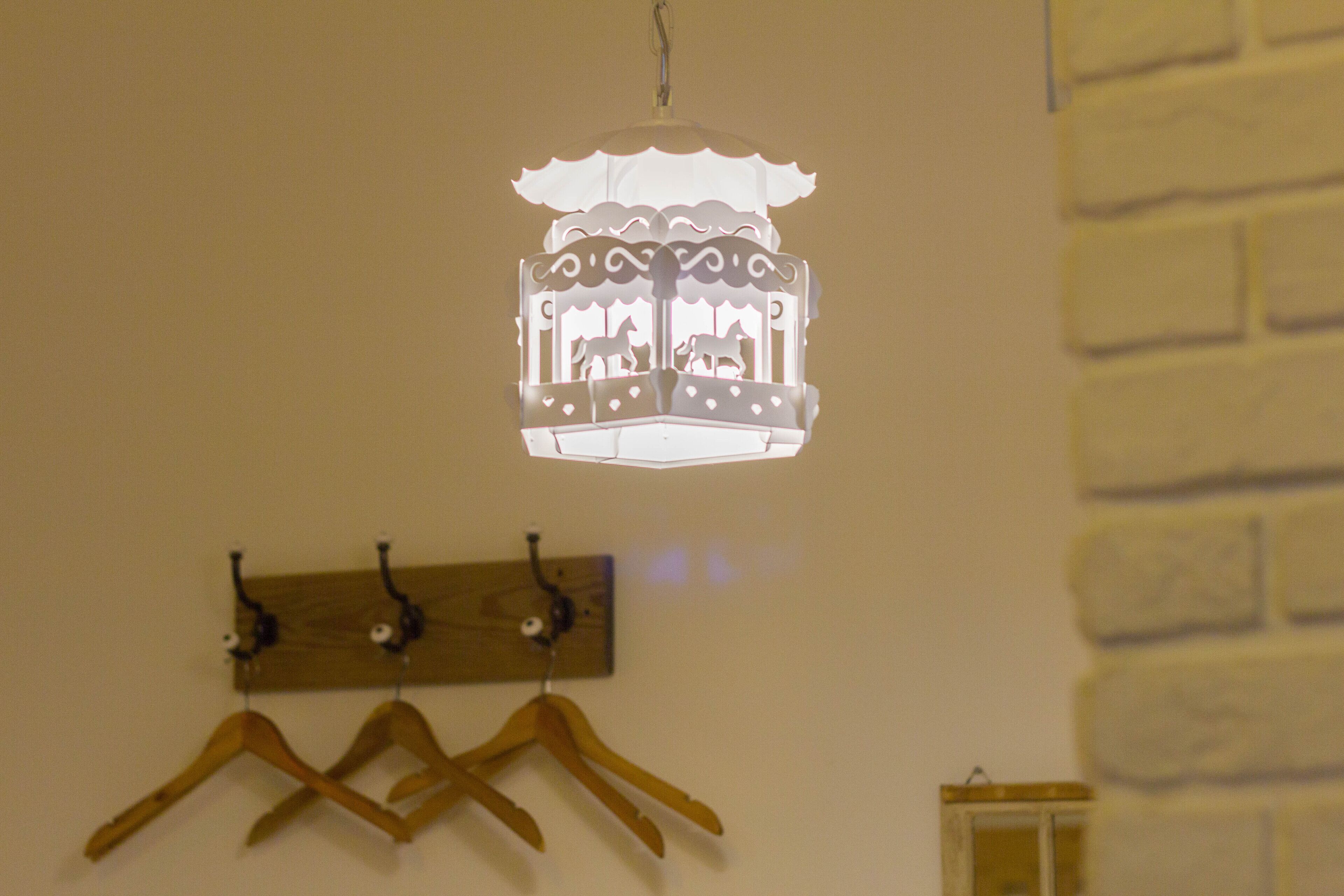 A white lantern with animal silhouettes hanging on a wall with wooden hangers.